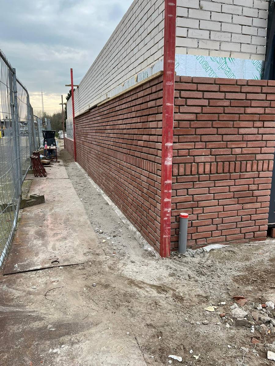 Rood gevelmetselwerk met rollaagdetail op een nieuwbouwproject